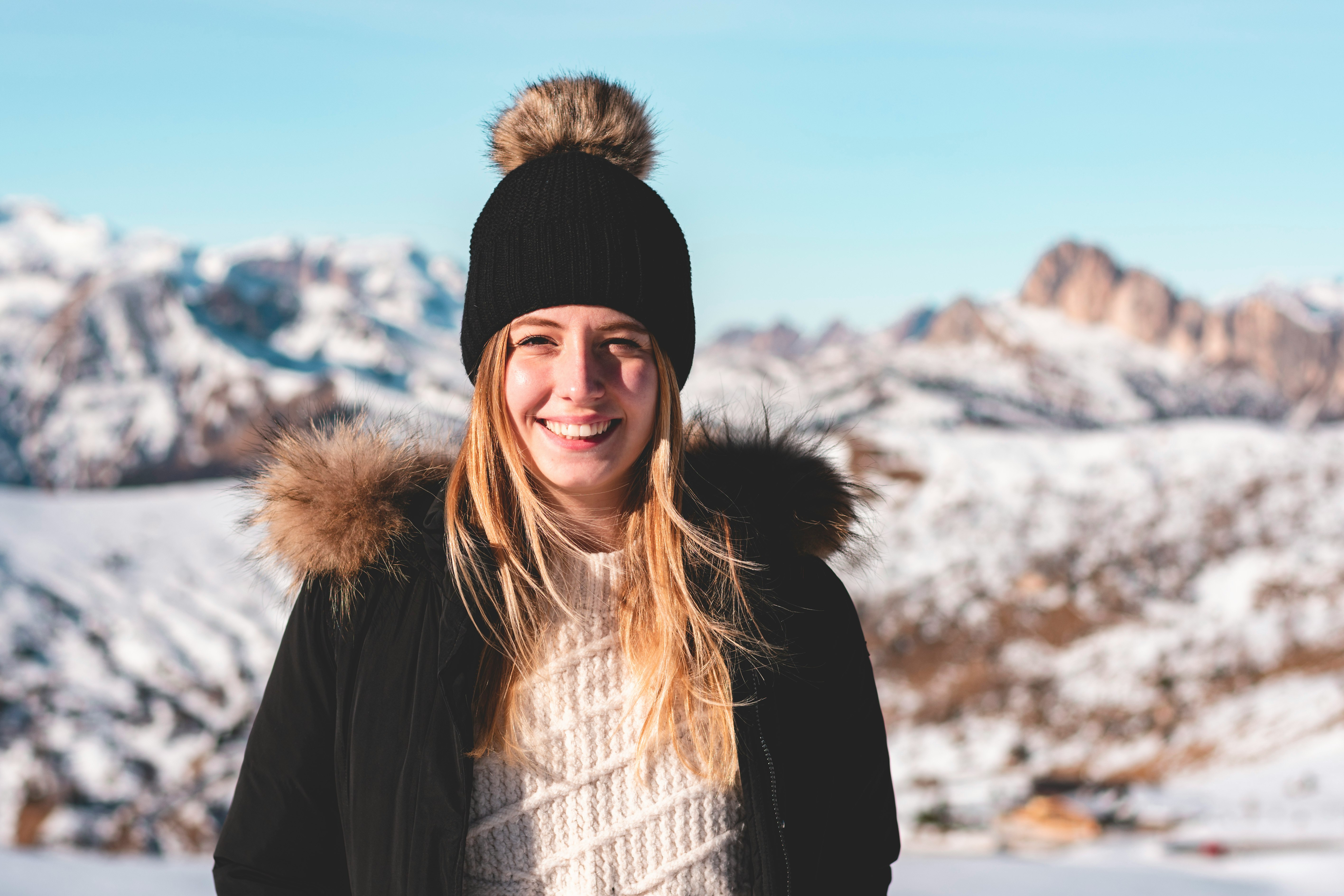 smiling woman standing while wearing black and brown parka coat